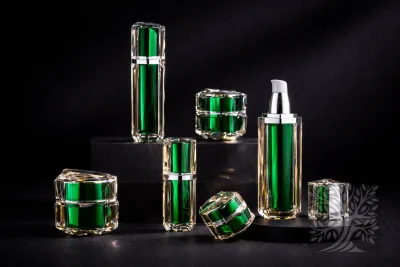 Emerald green faceted acrylic skincare bottles and cosmetic jars, displayed on tiered black stands with open container.