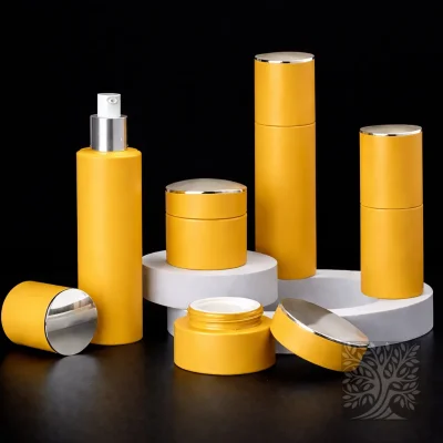 Bright yellow bottles and cosmetic jars with chrome caps, presented on layered white stands with open jar detail.