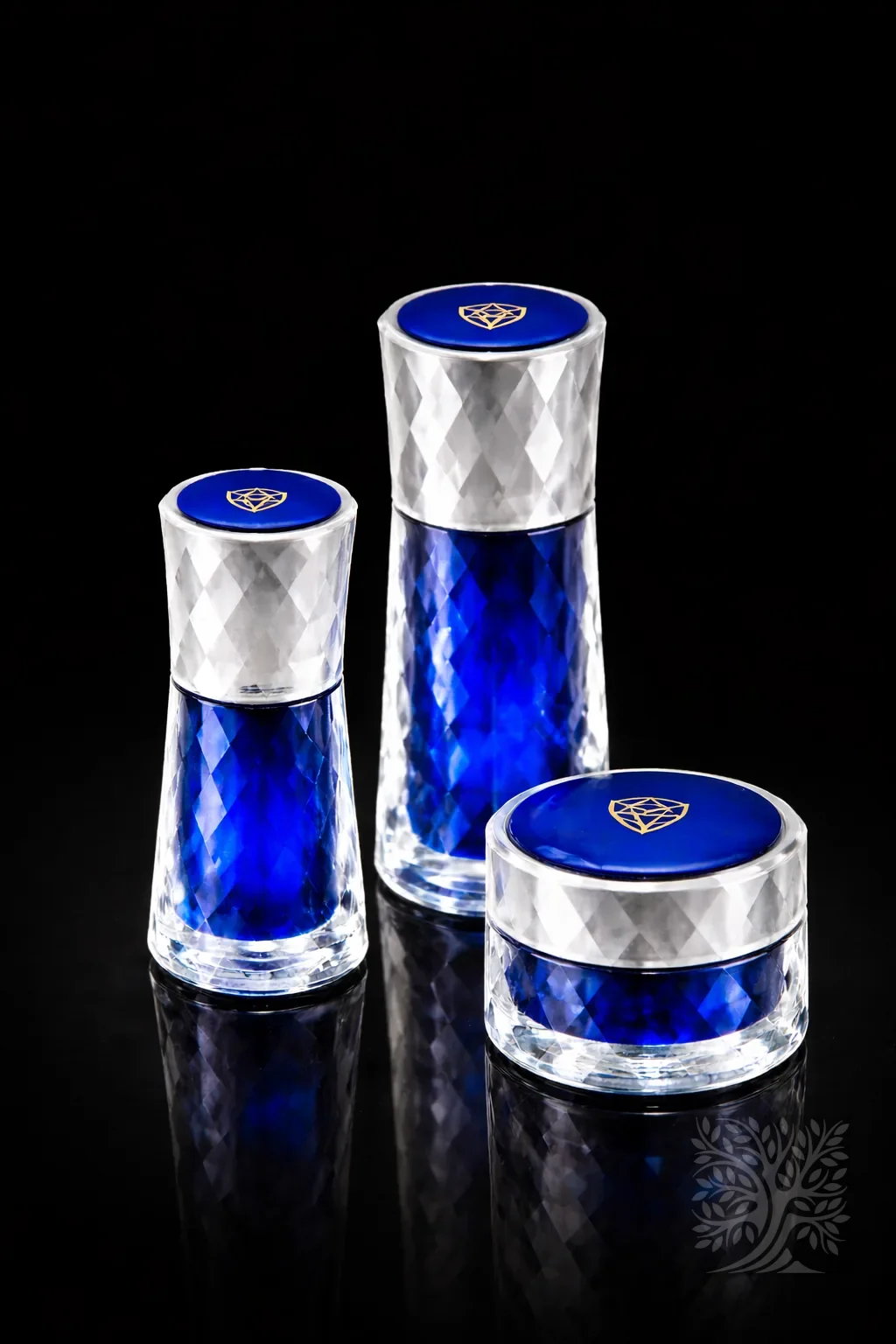 Crystal Prism faceted acrylic skincare bottles and jar with cobalt blue inner tone and clear outer shell design.