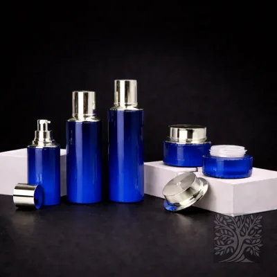 Gloss cobalt blue glass bottles and cosmetic jars with silver caps, displayed in a clean Cocktail packaging arrangement.