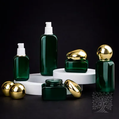 Deep green glass bottles and cosmetic jars with gold caps, including a pump bottle, presented in a balanced elevated display.