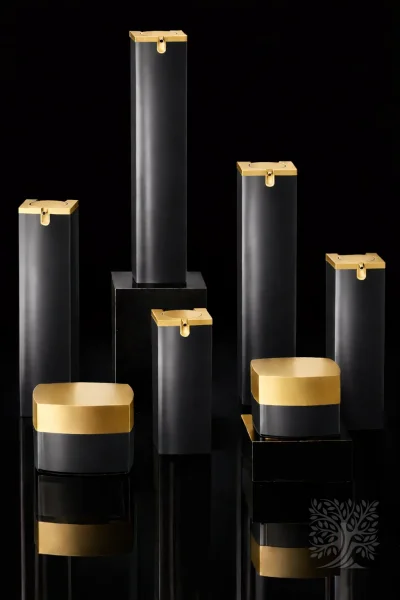 Matte black skincare bottles and cosmetic jars with gold caps, arranged on black display blocks in a structured layout.