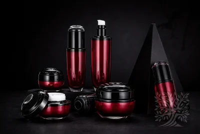 Rich red gradient acrylic skincare bottles and cosmetic jars with black caps, arranged on tiered blocks with open jar display.